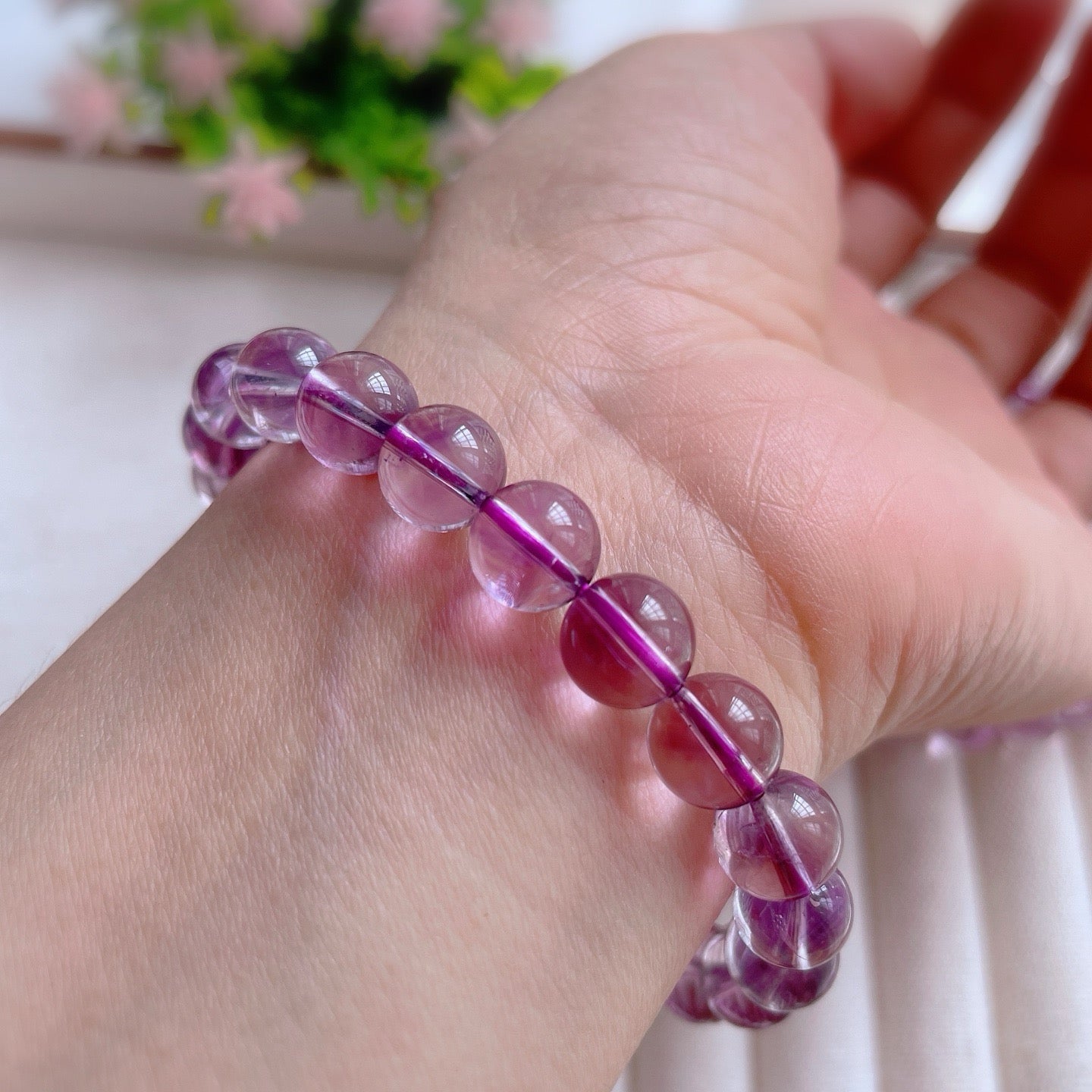 Hand wearing a purple beaded bracelet with a blurred background