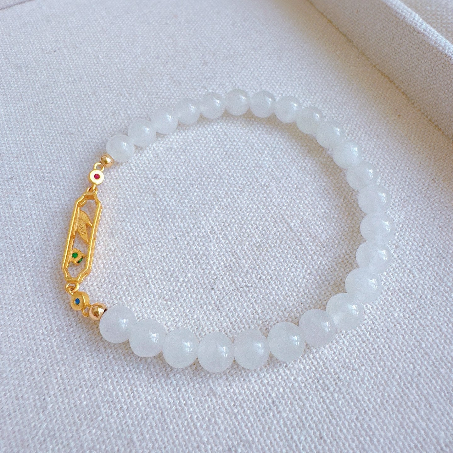 Beaded bracelet with a gold clasp on a white fabric background